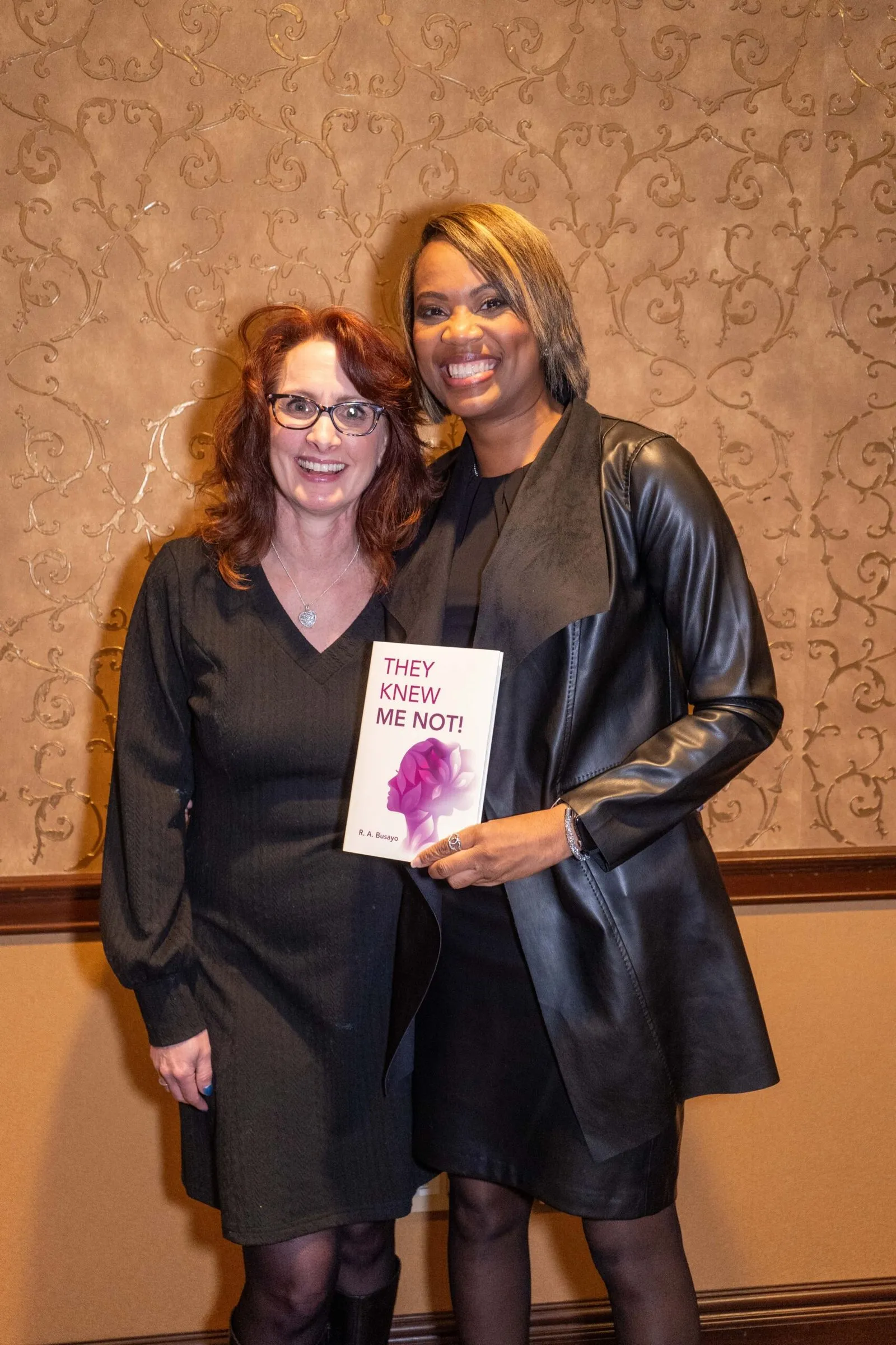 Rosa Allison in a black leather jacket, smiling beside a guest at her book launch.