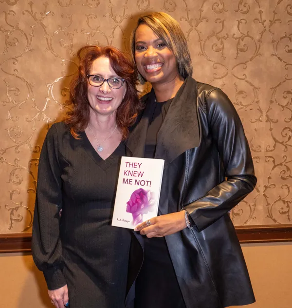 Rosa Allison holding her book beside a guest at the launch